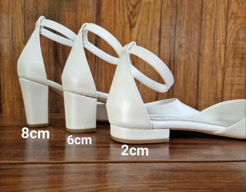 May include: Three pairs of white heeled sandals with ankle straps. The heels are 8 cm, 6 cm, and 2 cm tall.