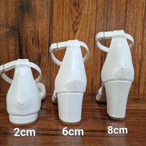 May include: Three pairs of white heeled sandals with ankle straps. The heels are 2 cm, 6 cm, and 8 cm tall.