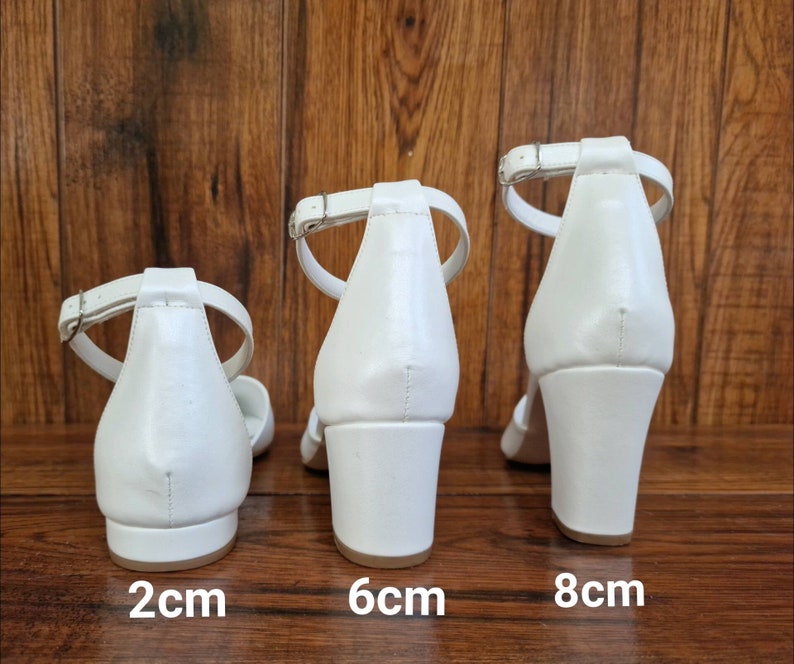 May include: Three pairs of white heeled sandals with ankle straps. The heels are 2 cm, 6 cm, and 8 cm tall.
