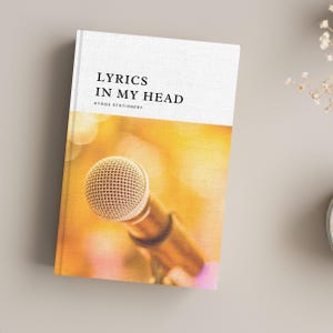 May include: A white notebook with the text "Lyrics in My Head" and "Hygge Stationery" printed on the front cover. The background image is a close-up of a gold microphone.