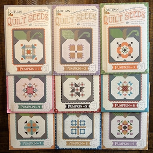 May include: Nine quilt seed packets with pumpkin designs. Each packet features a different pumpkin block pattern, with the text "Pumpkin No. 1" through "Pumpkin No. 9". The packets have a fall theme with the text "Autumn" and "Quilt Seeds".