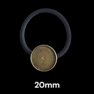 May include: A black elastic hair tie with a round, brass-colored bezel. The bezel is 20mm in diameter. The image is set against a black background.