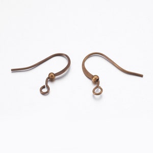 May include: Two antique bronze-colored earring hooks. Each hook features a curved design with a small ball and a loop at the bottom for attaching charms or beads. The hooks are designed for pierced ears.