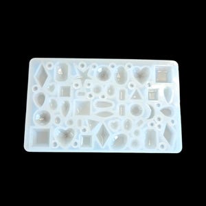 May include: A clear, rectangular silicone mold with various shapes, including hearts, squares, diamonds, and stars. The mold is designed for crafting resin jewelry or decorative elements. The shapes are of different sizes and are arranged closely together.