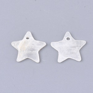 May include: Two white, star-shaped pendants with a pearlescent sheen. Each pendant has a small hole at the top for stringing. The pendants are likely for jewelry making or other craft projects.