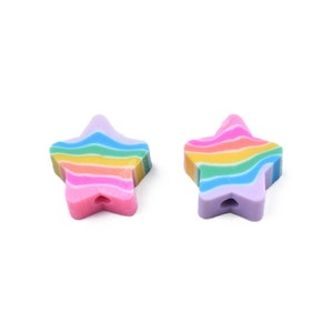May include: Two star-shaped beads with a rainbow striped design. The beads have a hole for stringing and are in shades of pink, yellow, blue, and purple. The beads are on a white background.