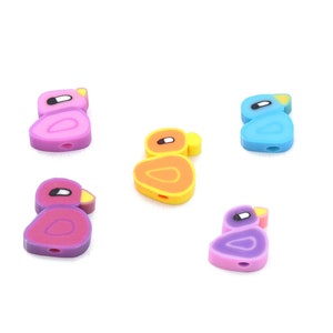 May include: Five colorful duck-shaped beads in shades of pink, purple, orange, and blue. Each bead has a white eye, a yellow beak, and a hole for stringing. These polymer clay beads are ideal for jewelry making and crafts.