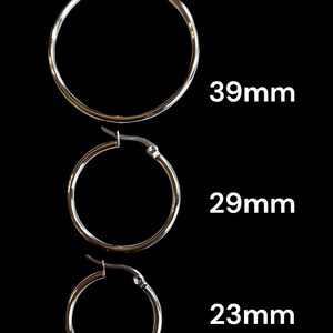 Peut inclure: Trois boucles d'oreilles cr&eacute;oles argent&eacute;es de diff&eacute;rentes tailles sont pr&eacute;sent&eacute;es sur fond noir. Les tailles sont de 39 mm, 29 mm et 23 mm. Les boucles d'oreilles ont un design simple avec une fermeture &agrave; charni&egrave;re.