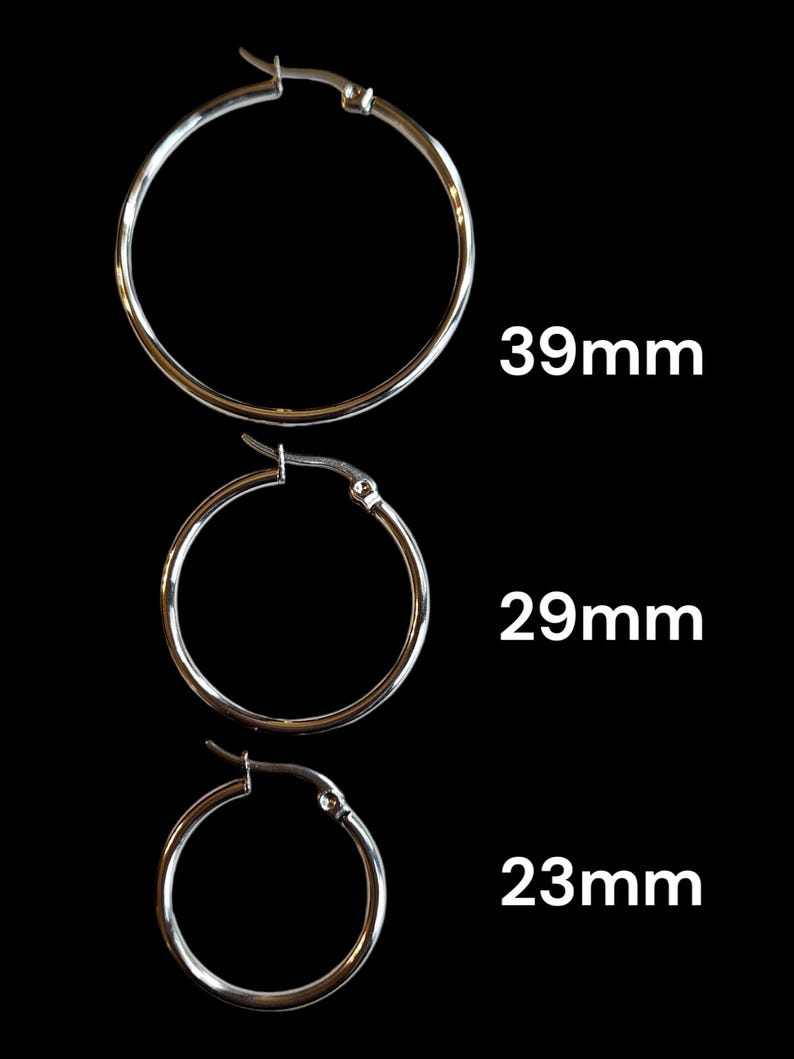 Peut inclure: Trois boucles d'oreilles cr&eacute;oles argent&eacute;es de diff&eacute;rentes tailles sont pr&eacute;sent&eacute;es sur fond noir. Les tailles sont de 39 mm, 29 mm et 23 mm. Les boucles d'oreilles ont un design simple avec une fermeture &agrave; charni&egrave;re.
