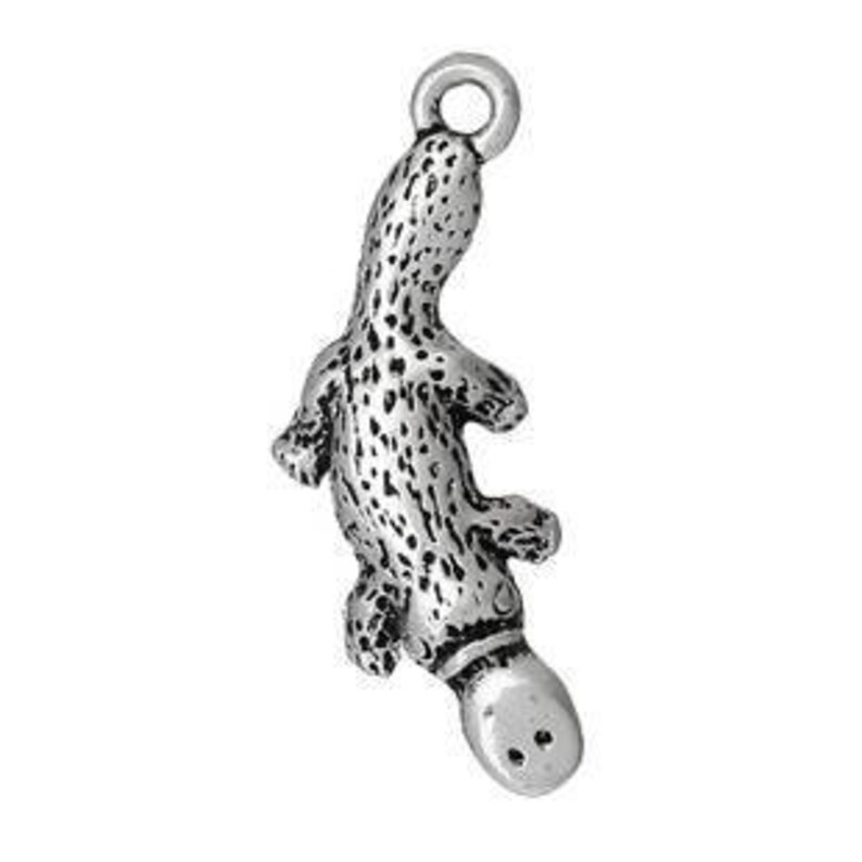 May include: A silver-colored platypus charm with a textured body and a small loop at the top for attaching to a necklace or bracelet. The charm has a detailed design, including the platypus's bill and webbed feet.