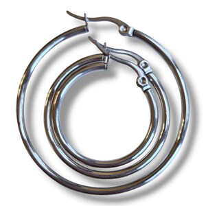 Peut inclure: Trois boucles d'oreilles cr&eacute;oles argent&eacute;es de tailles diff&eacute;rentes sont pr&eacute;sent&eacute;es. Les boucles d'oreilles sont en m&eacute;tal brillant et ont un design circulaire classique. Les cr&eacute;oles sont reli&eacute;es par un fermoir &agrave; charni&egrave;re. Les boucles d'oreilles sont pr&eacute;sent&eacute;es sur fond blanc.