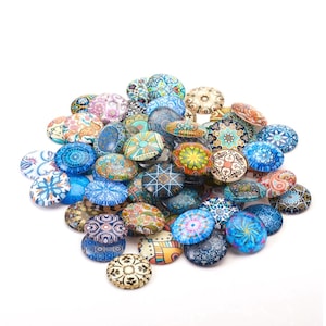 May include: A collection of decorative glass magnets with various colorful patterns. The designs include floral, geometric, and abstract motifs in shades of blue, orange, green, and purple. The magnets are oval-shaped and arranged on a white background.