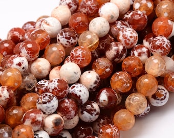 May include: Close-up of a collection of round gemstone beads in shades of orange, brown, and white. The beads have a faceted texture and a marbled appearance, suitable for jewelry making or crafting projects.