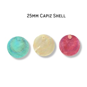 May include: Three 25mm Capiz shell discs in shades of teal, cream, and red. Each disc is round with a small hole at the top. The teal disc has an iridescent sheen, the cream disc is opaque, and the red disc has a textured surface.