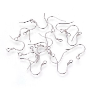 May include: A collection of silver-colored earring hooks, scattered on a white surface. Each hook features a curved design with a looped end and a coiled spring detail near the top. The hooks are made of a shiny, metallic material.