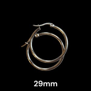 Peut inclure: Boucles d'oreilles cr&eacute;oles argent&eacute;es, 29 mm de diam&egrave;tre, sur fond noir. Les boucles d'oreilles sont circulaires avec une fermeture &agrave; charni&egrave;re. Le texte "29mm" est affich&eacute; en blanc, indiquant la taille des boucles d'oreilles.