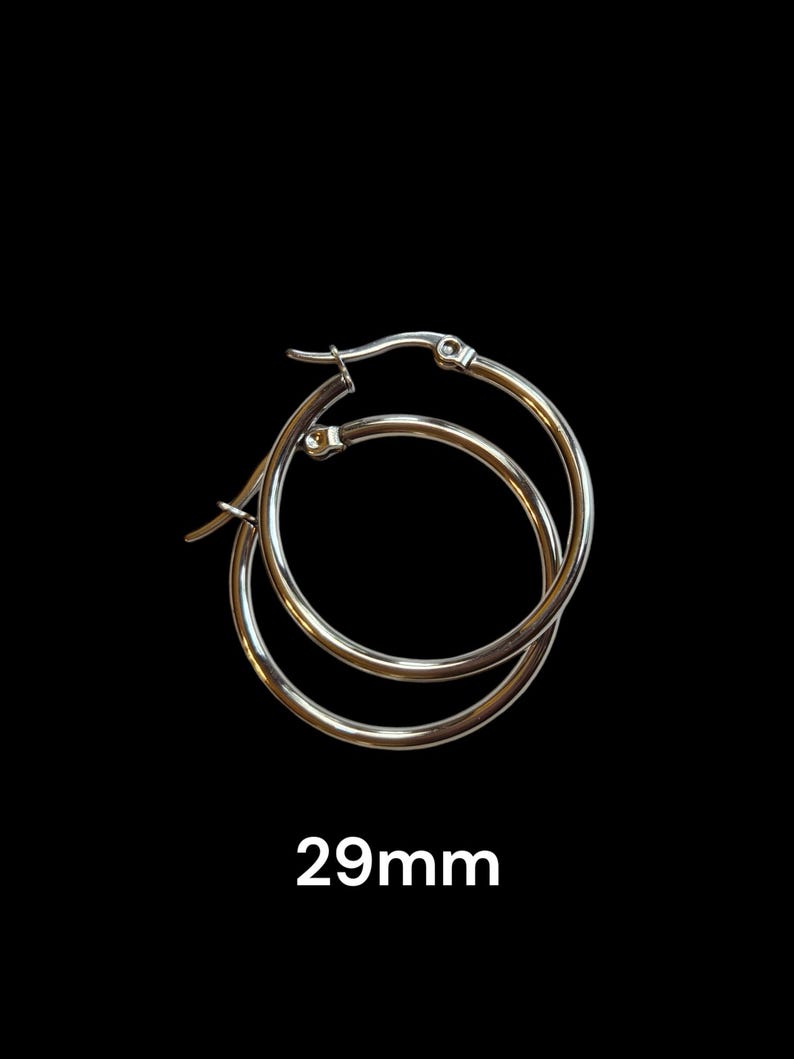 Peut inclure: Boucles d'oreilles cr&eacute;oles argent&eacute;es, 29 mm de diam&egrave;tre, sur fond noir. Les boucles d'oreilles sont circulaires avec une fermeture &agrave; charni&egrave;re. Le texte "29mm" est affich&eacute; en blanc, indiquant la taille des boucles d'oreilles.