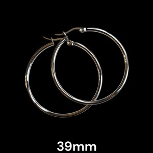Peut inclure: Une paire de boucles d'oreilles cr&eacute;oles argent&eacute;es sur fond noir. Les boucles d'oreilles sont circulaires, avec un design simple et poli. Le texte "39mm" est affich&eacute; en dessous, indiquant leur taille, soit environ 3,9 cm.