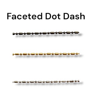 May include: Three strands of faceted dot dash chains in black, gold, and silver. The chains are displayed against a white background. The text "Faceted Dot Dash" is at the top of the image.