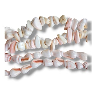 May include: Three strands of natural seashell beads in shades of white and pale pink. The top two strands feature irregular, chip-like beads, while the bottom strand is made of small, conch-like shells.