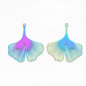 May include: Two iridescent metal ginkgo leaf charms. Each charm has a stem with a small loop at the top and a fan-shaped leaf with detailed veining. The colors shift from purple to blue and green.