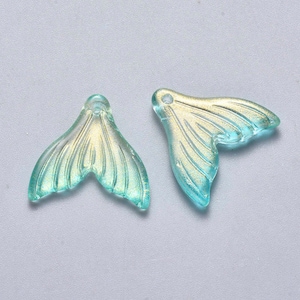 May include: Two translucent blue-green mermaid tail charms with gold glitter accents. The charms are made of a clear material and have a hole at the top for stringing. The mermaid tail charms are ideal for jewelry making or craft projects.