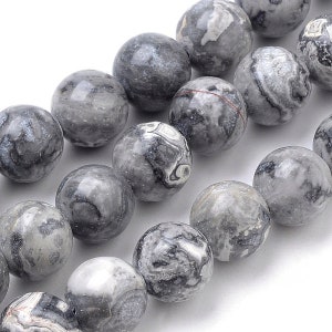 May include: Close-up of a strand of gray and white marbled gemstone beads. The round beads have a polished finish and vary in pattern, with swirls and veins of color. The beads are strung together, ready for jewelry making.