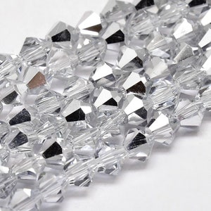 May include: Close-up of clear, faceted crystal beads. The beads are strung together, showcasing their multiple reflective surfaces. The crystals are a bright, silvery color, reflecting light and creating a sparkling effect. Ideal for jewelry making or craft projects.