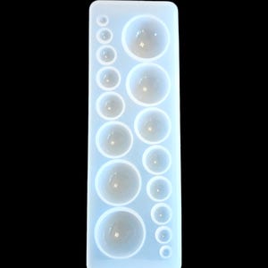 May include: A clear, rectangular silicone mold with various sized, rounded cavities. The mold is designed for crafting resin or other materials into spherical shapes. The cavities range in size, offering versatility for different projects. The mold is set against a black background.