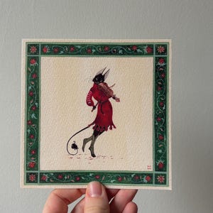 Op de afbeelding: Een vierkante kunstdruk met een duivelachtige figuur in een rode outfit die viool speelt. Het kunstwerk is omlijst met een groene rand versierd met rode bloemaccenten. De achtergrond is een neutraal beige.