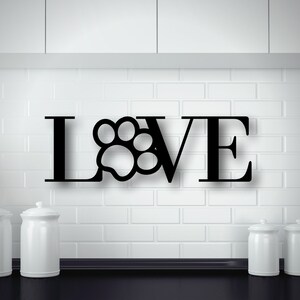 May include: Black metal wall decor with the word "LOVE" with a paw print replacing the "O".