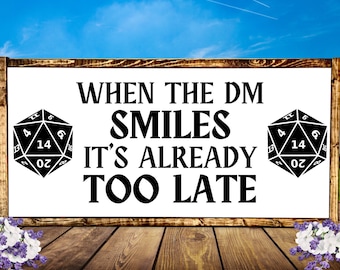 May include: A white sign with black text and a black and white dice graphic. The text reads "When the DM smiles it's already too late".