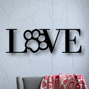 May include: Black metal wall decor with the word "LOVE" with a paw print in place of the "O".
