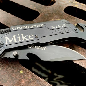 May include: Black pocket knife with a silver inscription that reads "Groomsman Mike 3-14-19".