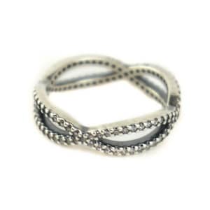 May include: A silver ring with a twisted design and small clear stones.