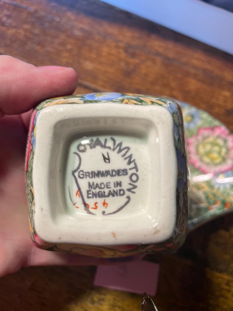 Może przedstawiać: Kwadratowy ceramiczny kubek w kwiaty z napisem "Royal Winton Grimwades Made in England" na spodzie. Kubek ma kolorowy wz&oacute;r z r&oacute;żowymi, niebieskimi i ż&oacute;łtymi kwiatami. Częściowo widoczny jest pasujący spodek.