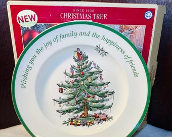 May include: A white Christmas Tree plate with a green rim and a detailed illustration of a decorated Christmas tree. The plate has the text "Wishing you the joy of family and the happiness of friends". The plate is in front of a red box that says "CHRISTMAS TREE" and "NEW".