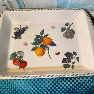 May include: Rectangular white serving dish with a fruit design. The dish features illustrations of oranges, plums, pears, cherries, and other fruits. A green and pink floral border frames the edges of the dish.