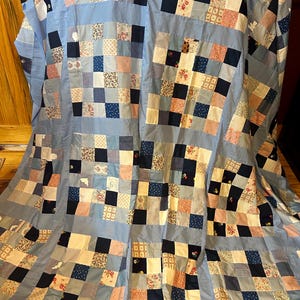 以下が含まれることがあります： 黒い持ち手が付いた白いセラミックマグカップ。黒い太字で「But First, Coffee」と書かれています。マグカップはぼやけた背景に置かれ、居心地の良い環境を示唆しています。