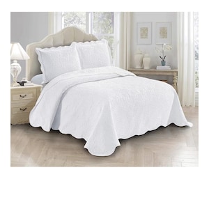 May include: White bedspread set with a floral pattern. The set includes a bedspread and two pillow shams. The bedding is displayed on a bed with a headboard and nightstand. The room has a neutral color scheme.