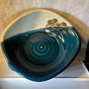 May include: A set of three ceramic mugs with a speckled, matte finish. The mugs are in shades of cream, light gray, and dark gray. Each mug has a simple, minimalist design, perfect for coffee or tea.