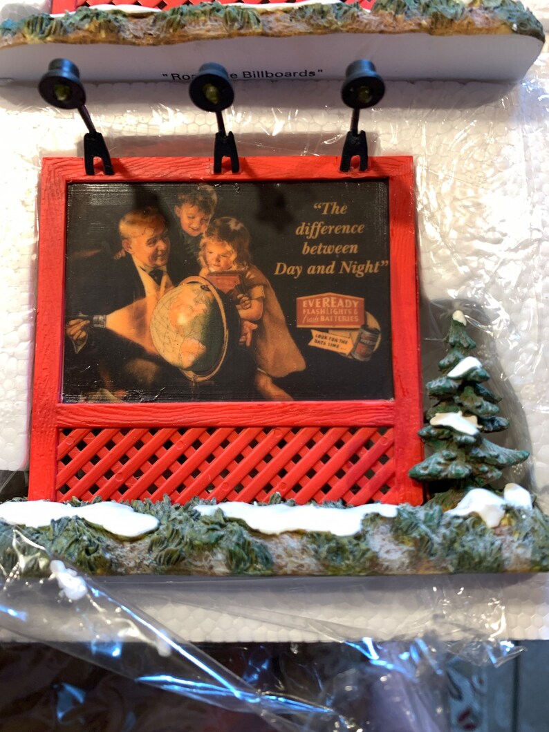 May include: A red and white miniature billboard with a vintage advertisement for Eveready Flashlights and Batteries. The ad features a family looking at a globe and the text "The difference between Day and Night".