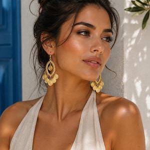 May include: Gold-toned dangle earrings featuring an oval filigree frame with a central circular medallion and a series of smaller, dangling circular coin-like charms suspended from the bottom edge, attached with standard earring hooks.
