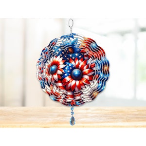 Pode incluir: Um moinho de vento de metal com um design de girassol vermelho, branco e azul. O moinho de vento tem um prisma de cristal pendurado na parte inferior.