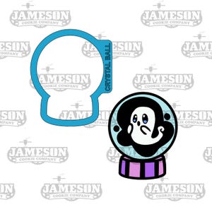 May include: A blue cookie cutter in the shape of a snow globe with a ghost inside. The snow globe is on a base with purple and white stripes. The cookie cutter is on a white background.