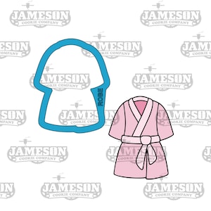 Puede incluir: Un cortador de galletas azul en forma de bata con la palabra "ROBE" escrita en él. Una bata rosa con cuello blanco y cinturón se muestra junto al cortador de galletas.