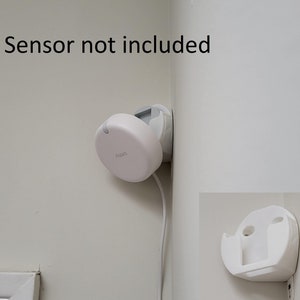 May include: White wall mount for a smart home sensor, with the text "Sensor not included". The mount is attached to a white wall in a corner. A white sensor is shown mounted to the wall mount. The sensor is connected to a white wire.