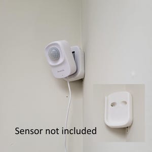 May include: White wall mount for a motion sensor, with the text "Gosund Life" on the device. The sensor is not included. A separate white wall mount is shown on the right side of the image.
