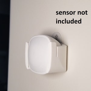 May include: White wall mount for a motion sensor. The text "sensor not included" is printed above the mount.