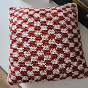Puede incluir: Un coj&iacute;n de tiro de cuadros rojos y blancos con textura de ganchillo.